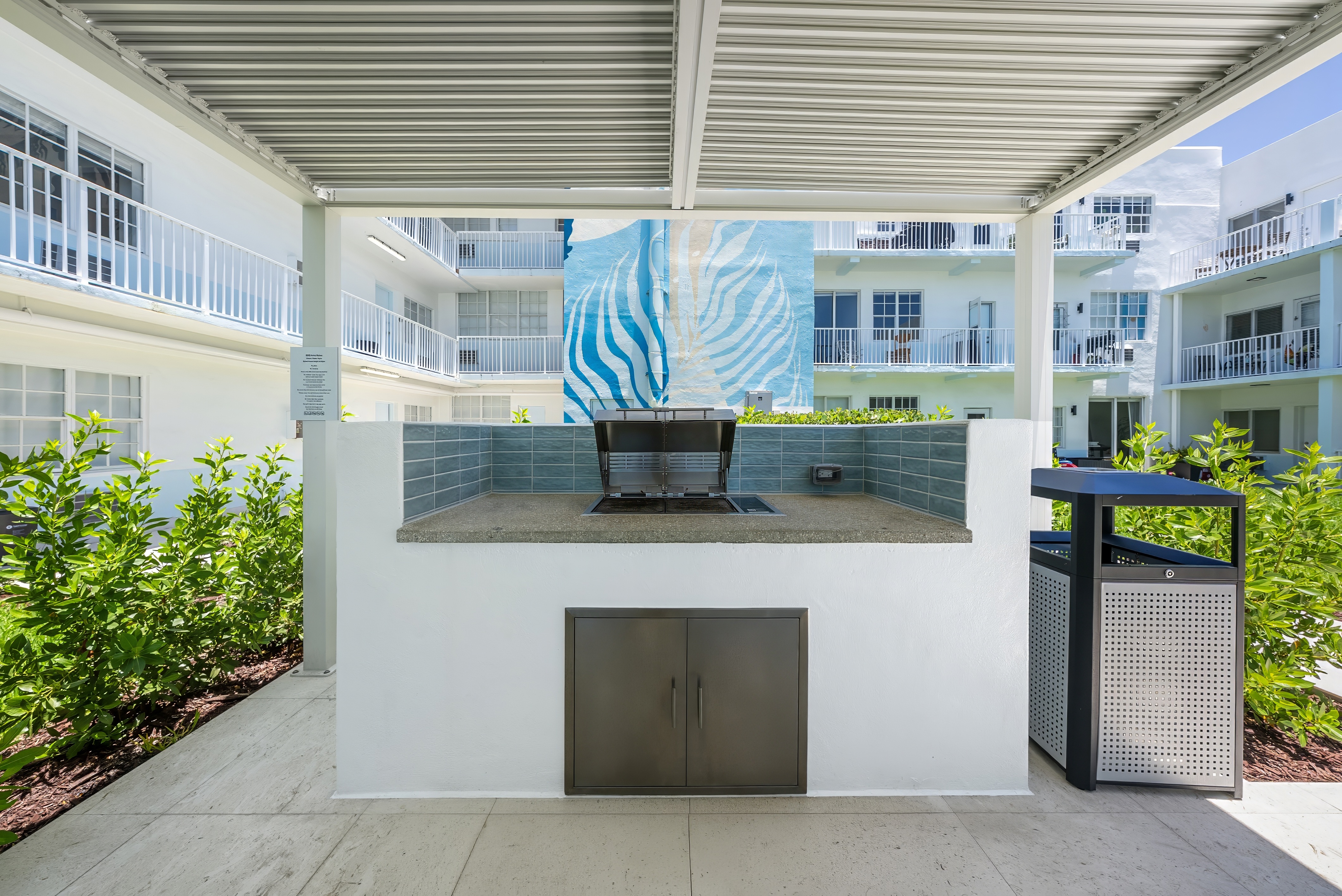 A white building with a black door and a glass table with a blue and white mural in the background.